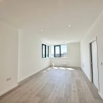Spacious, bright empty room with wooden flooring.