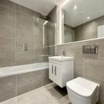 Modern bathroom with grey tiles and white fixtures.