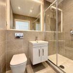 Modern bathroom with shower and beige tiles.