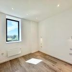 Bright empty room with wooden floor and large window.