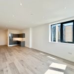Spacious modern apartment with large windows and wooden flooring.