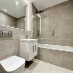 Modern grey-tiled bathroom with bathtub and vanity.