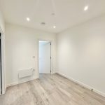 Modern empty room with wooden flooring and white walls.