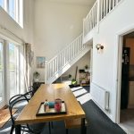 Bright dining area with staircase and kitchen view.