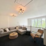 Modern living room with grey sofa and wicker chair.