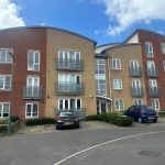 Modern apartment building with parked cars outside.