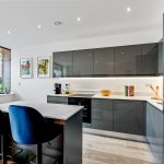 Modern kitchen with island and dark cabinets.