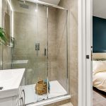 Modern ensuite bathroom with shower and bedroom view.