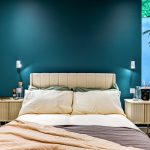 Modern bedroom with teal accent wall and bed.