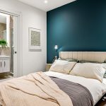 Modern bedroom with ensuite bathroom and teal feature wall.