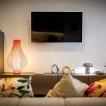 Modern living room with lamp, TV, and cushions.