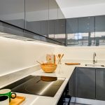 Modern kitchen with grey cabinets and wooden utensils.