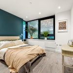 Modern bedroom with blue accent wall and plants.