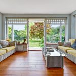 Bright conservatory with garden view and sofas.