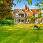 Red-brick house with garden and deer statues.