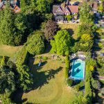 Aerial view of house with garden and swimming pool.