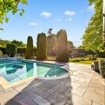Sunny garden with swimming pool and trees.