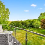 Garden view from balcony with glass railing.