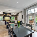 Modern kitchen with black table and large windows.