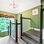 Green-walled staircase with plants and window.