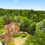 Aerial view of house surrounded by lush greenery.