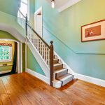 Wooden staircase in bright hallway with green walls.