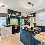 Modern kitchen with blue island and white cabinets.