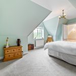 Cosy loft bedroom with pastel walls and attic window.