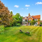 Country house with large garden and grazing deer.
