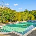 Sunny garden with a swimming pool and seating area.