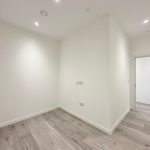 Empty room with wooden flooring and white walls.