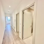 Bright hallway with wooden flooring and open doors.