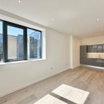 Bright modern kitchen with large window and grey cabinets.