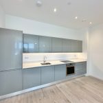 Modern kitchen with sleek, grey cabinetry and appliances.