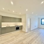 Modern kitchen with grey cabinets and wooden floor.