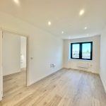 Spacious, modern empty room with large window view.