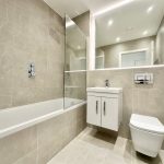 Modern bathroom with beige tiles and fixtures.