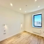 Bright empty room with wood floor and window view.