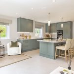 Modern kitchen with green cabinets and island seating.