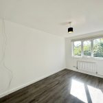 Empty room with large window and wooden floor