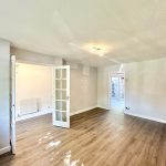Spacious, bright empty room with wooden floor.