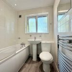 Modern white bathroom with bathtub and towel rail.