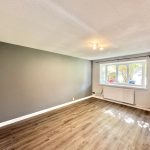 Modern unfurnished living room with large window and wood floor.