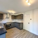 Modern kitchen with grey cabinets and wooden floor.