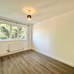 Empty room with wooden floor and large window.