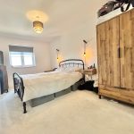 Modern bedroom with wooden wardrobe and black metal bed.