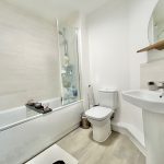 Modern bathroom with bathtub, toilet, and sink.