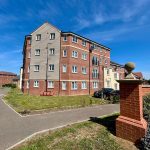 Modern brick apartment building with garden pathway.