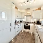 Modern kitchen with white cabinets and appliances.