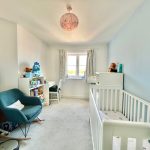 Bright nursery with cot, chair, toys, and desk.